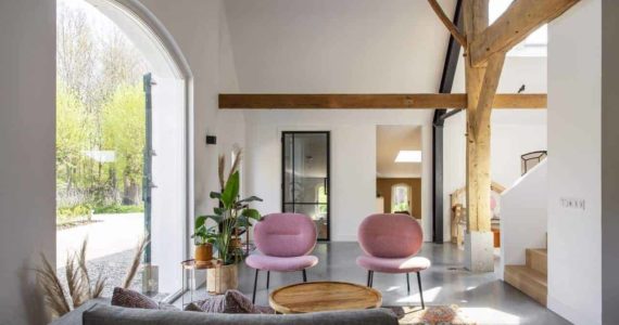 Gevlinderde betonvloer in de woonkamer in Ressen gecombineerd met een grijze bank en roze stoeltjes.