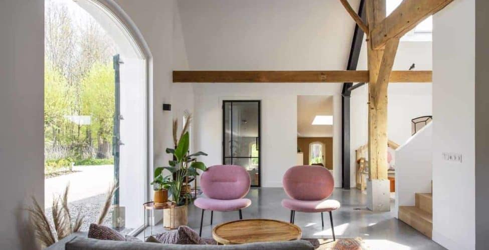 Gevlinderde betonvloer in de woonkamer in Ressen gecombineerd met een grijze bank en roze stoeltjes.