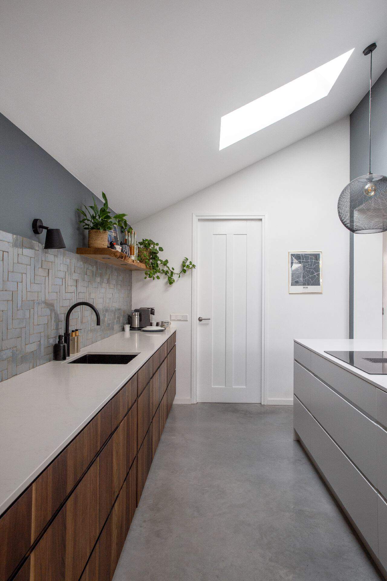 Houten keuken in Breda met een wit kookeiland op een gevlinderde betonvloer.