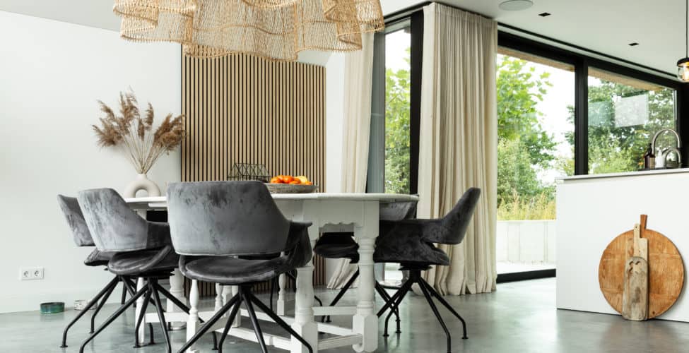 Woning in Nuenen met een gevlinderde betonvloer van Willem Designvloeren. Hierop staat een witte eettafel met daaraan grijze stoelen. Ook staat er een wit kookeiland op de gevlinderde betonvloer.