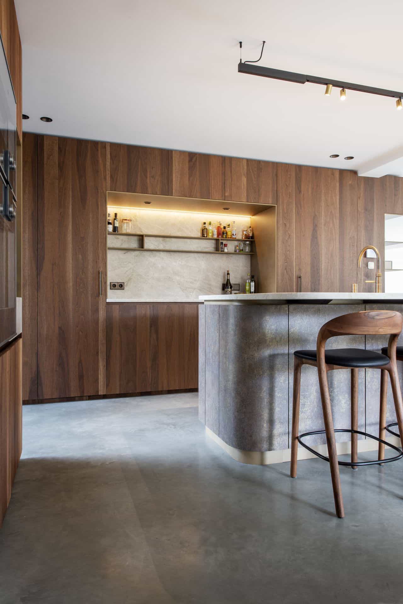 Bruine keukenkasten met een roestkleurig keukeneiland op een gevlinderde betonvloer in Waalwijk.