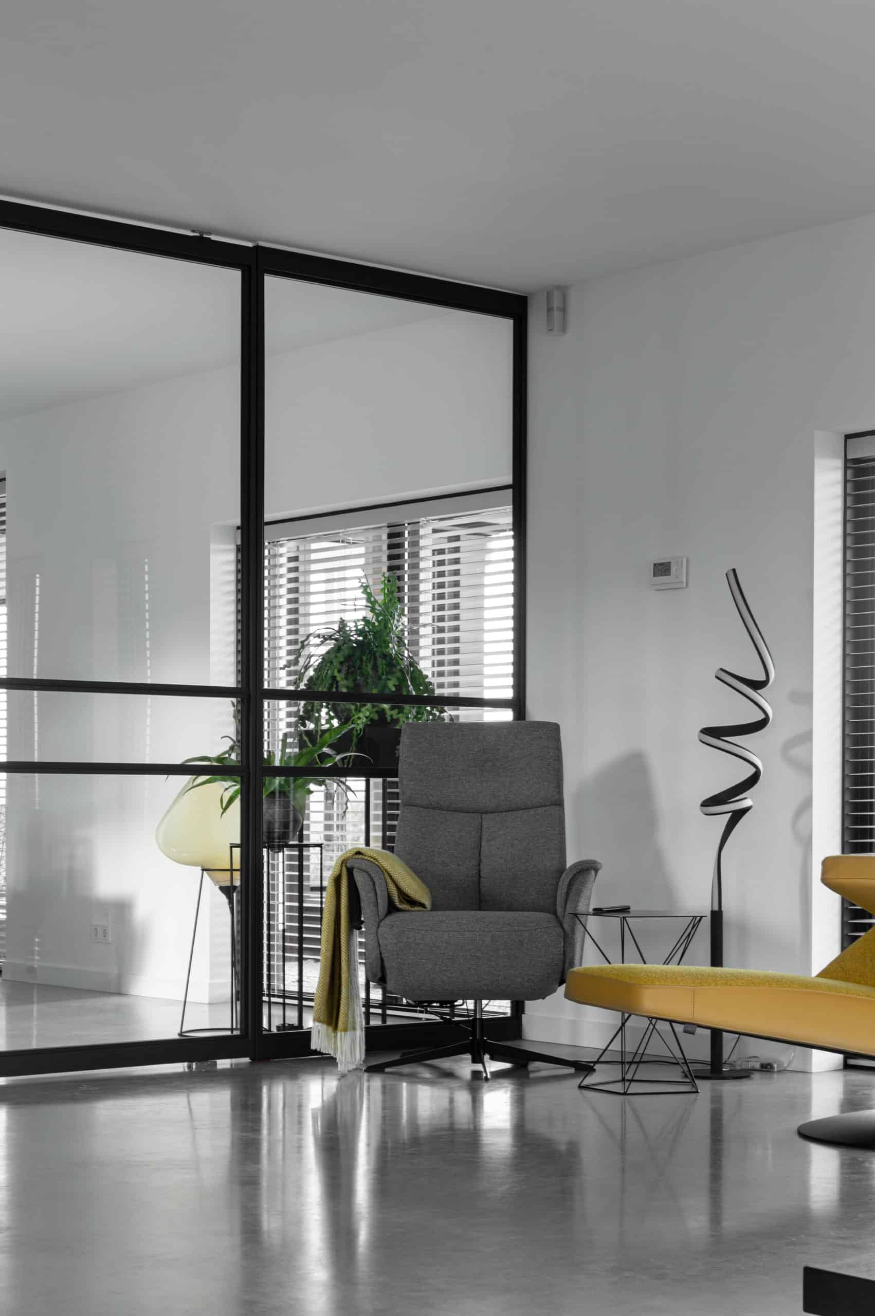 Zithoek in Bunschoten-Spakenburg met een gevlinderde betonvloer van Willem Designvloeren met daarop een grijze stoel en zwarte details.