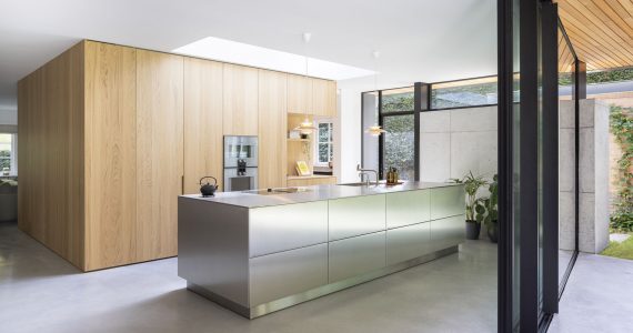 Aanbouw in Zeist met een gevlinderde betonvloer van Willem Designvloeren. Hierop staat een stalen kookeiland en een houten kastenwand. De gevlinderde betonvloer is ook doorgestort naar het gevlinderd betonnen terras buiten.