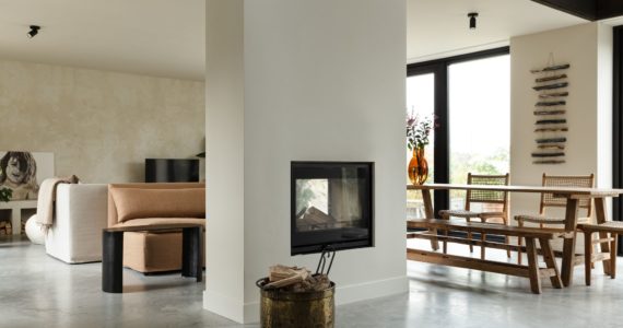 Eet- en woonkamer in Rijnsburg. Hiertussen zit een doorkijk haard. Als basis ligt er een gevlinderde betonvloer.