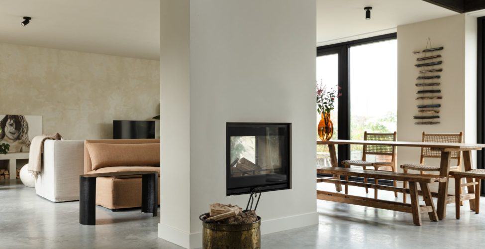 Eet- en woonkamer in Rijnsburg. Hiertussen zit een doorkijk haard. Als basis ligt er een gevlinderde betonvloer.