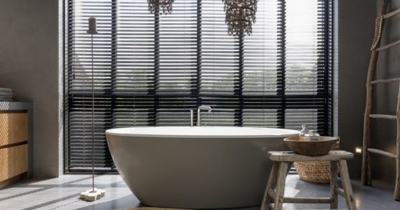 High-end badkamer voorzien van een gevlinderde betonvloer en beton ciré op de wanden. Op de betonvloer staat een wit vrijstaand bad.