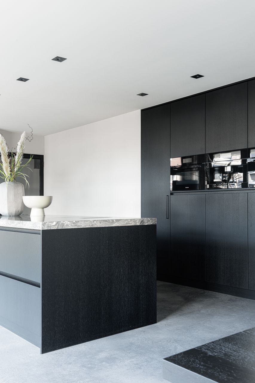 Italiaanse betonlook vloer in de kleur Rome in Opheusden gecombineerd met een zwarte keuken.