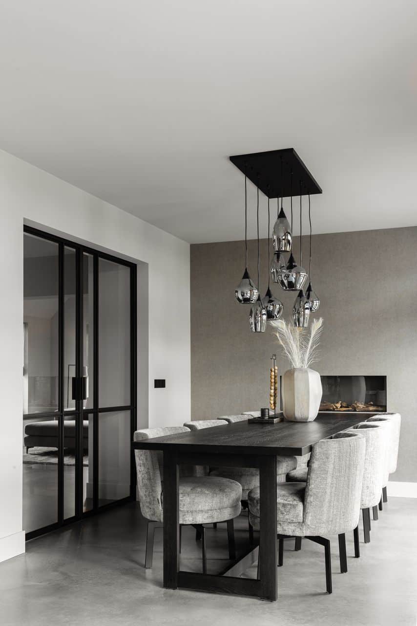 Italiaanse betonlook vloer in Opheusden met daarop een zwarte tafel en daaraan grijze stoelen.