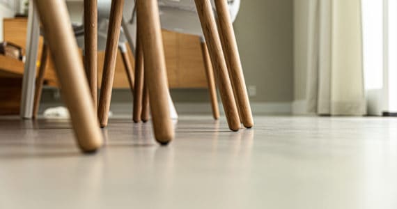 Italiaanse betonlook vloer in Soesterberg met daarop stoelen met houten poten.