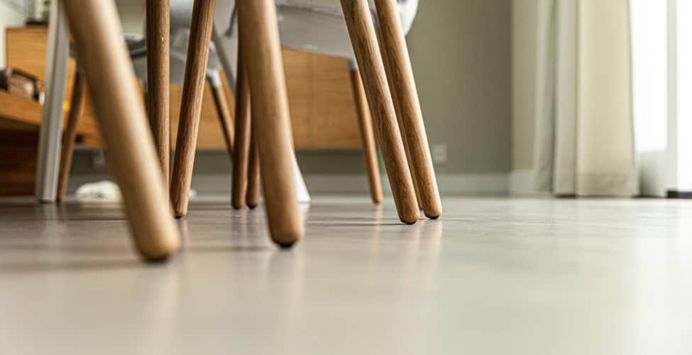 Italiaanse betonlook vloer in Soesterberg met daarop stoelen met houten poten.