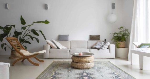 PU gietvloer van Willem Designvloeren in de woonkamer in Zeist. Hierop licht een licht gekleurd vloerkleed, staat een houten stoel en een beige bank. Ook staat er nog een grote plant op de PU gietvloer.