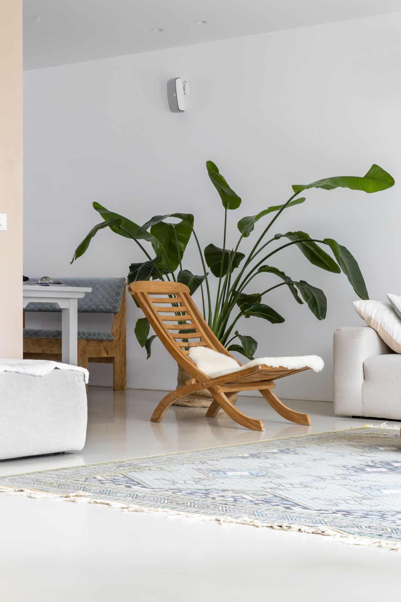 PU gietvloer van Willem Designvloeren in de woonkamer in Zeist. Hierop ligt een vloerkleed en staat een bruin stoeltje en een beige bank.