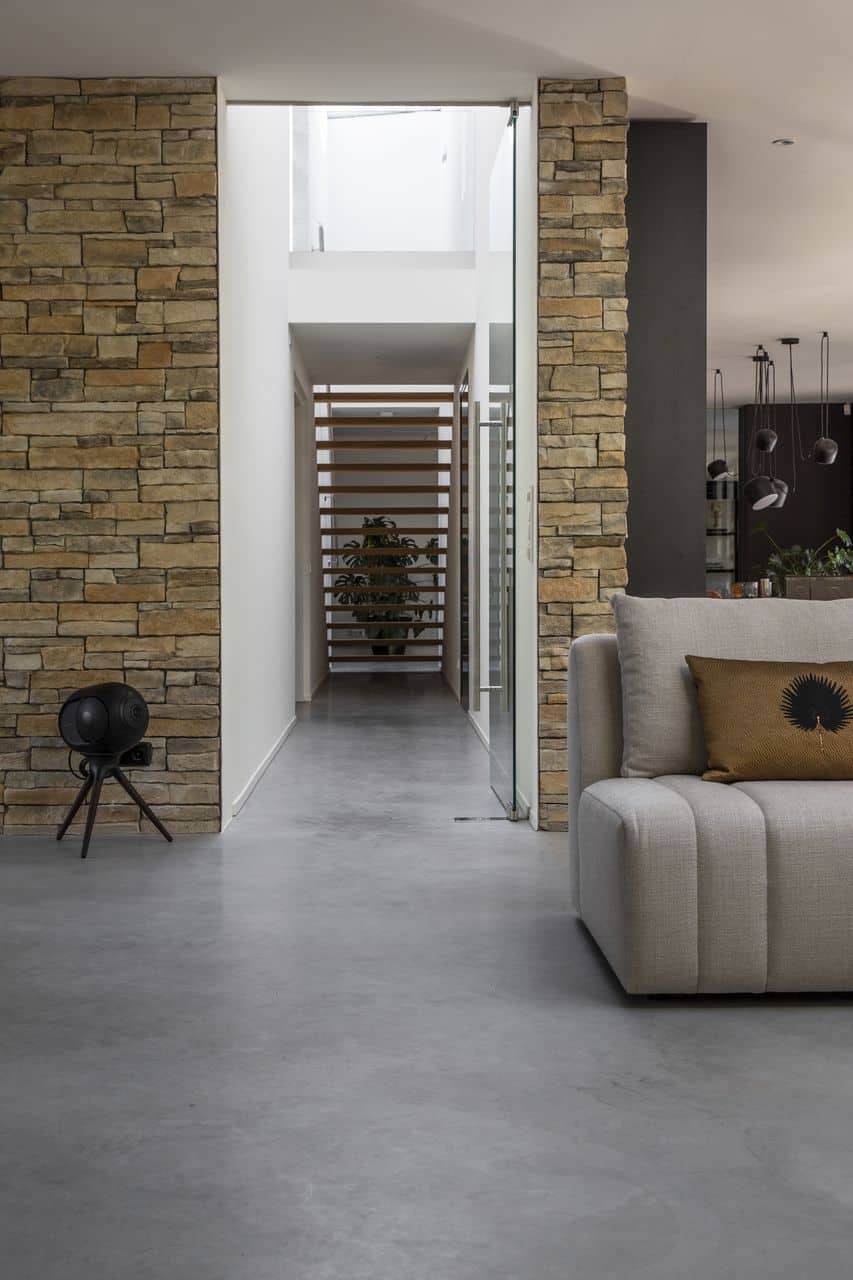 Gevlinderde betonvloer in Nijmegen in de hal en in de woonkamer. In de woonkamer staat een grijze bank.