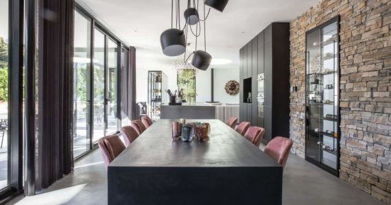 Gevlinderde betonvloer in Nijmegen gecombineerd met een stenen muur, zwarte tafel en daaraan roze stoelen.