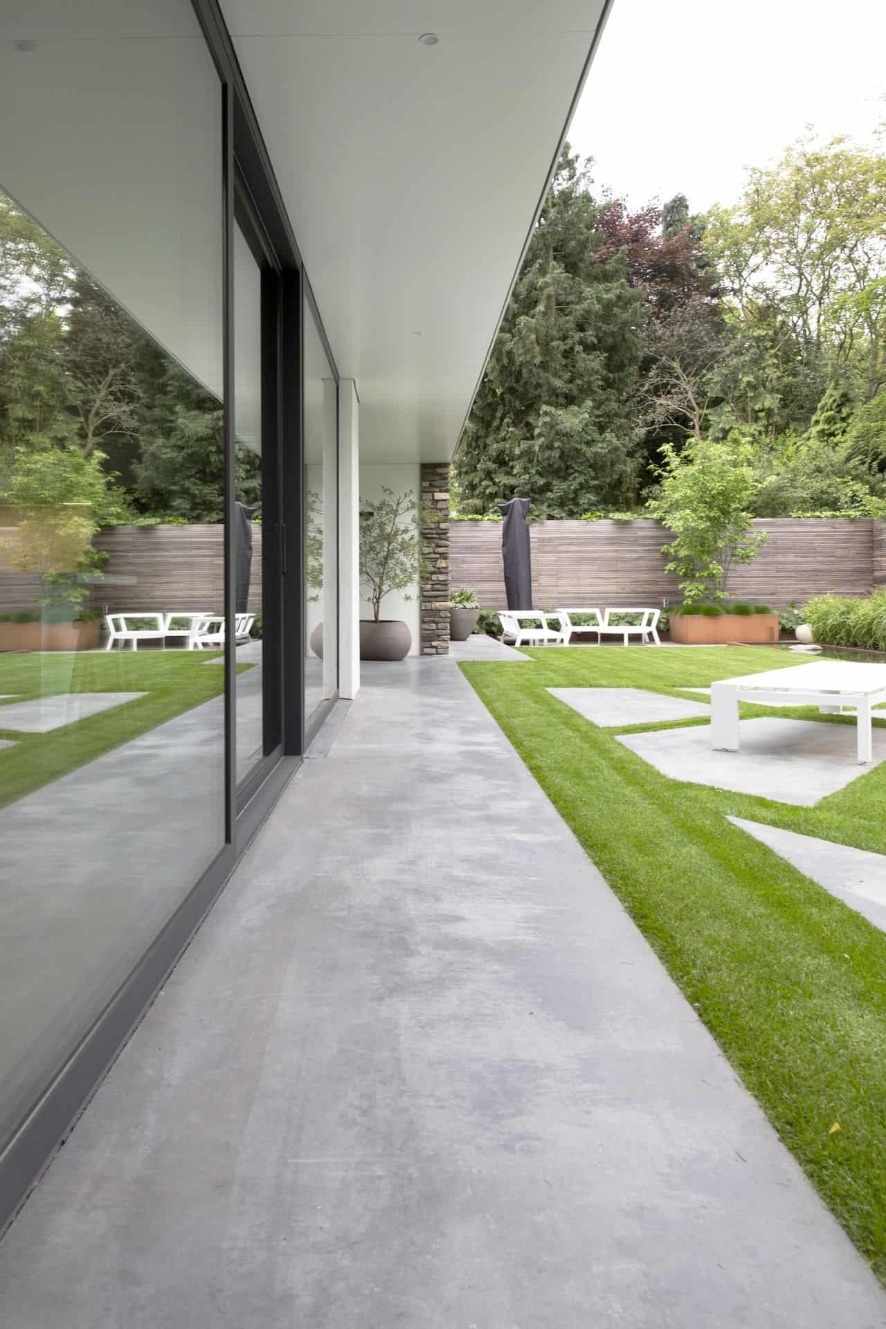 Bungalow in Oisterwijk met een gevlinderd betonnen terras van Willem Designvloeren in een looppad rondom het huis en in vlakken op het terras.