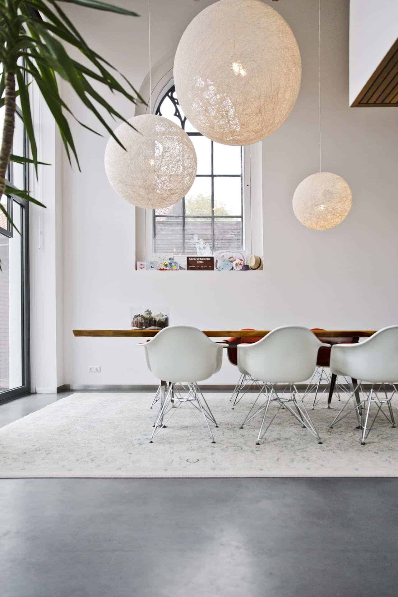 Gevlinderde betonvloer van Willem Designvloeren in de woning in een oud kerkje in Leerdam. Hierop staat een houten tafel met witte stoelen.