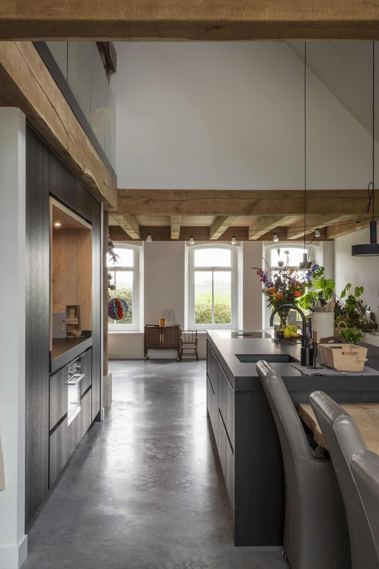 Zwarte keuken in Schagen met een gevlinderde beton vloer in een oude boerderijwoning